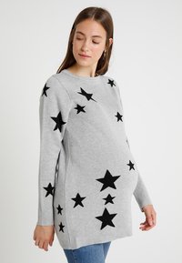 Suéter de maternidade cinza tricotado, com grandes apliques de estrela preta, mangas longas e decote redondo. Textura suave, corte descontraído.