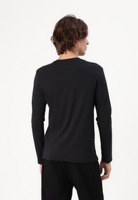 Langærmet sort t-shirt lavet af blødt stof, med en klassisk rund hals og et enkelt, tætsiddende design. Ingen bemærkelsesværdige mønstre eller detaljer.