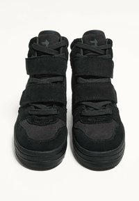 Scarpe da ginnastica nere con una combinazione di tomaie in suede e tessuto, dotate di tre cinturini in Velcro e di una suola imbottita, progettate per il comfort.