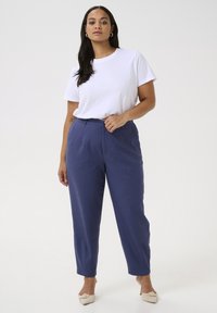 T-shirt blanc à manches courtes associé à un pantalon ample taille haute en navy avec un devant plat et une texture subtile.