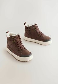 Braune High-Top-Stiefel mit weißem Fellfutter, braunen Schnürsenkeln und gummierter Zehenkappe. Strukturiertes Gewebe außen und gepolsterter Kragen für Komfort.
