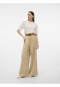 Top de punto blanco texturizado con mangas cortas abullonadas, combinado con pantalones de pierna ancha de talle alto en color beige y un cinturón marrón con hebilla circular.