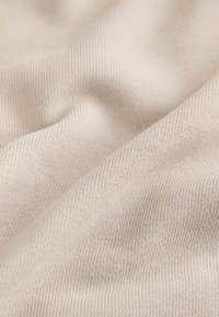 Tessuto elasticizzato beige chiaro con una superficie a coste, caratterizzato da linee sottili e una finitura morbida e liscia. Ideale per abbigliamento o tessuti per la casa.