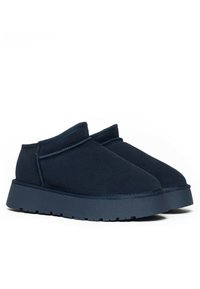 Granatowe buty wsuwane o miękkiej zamszowej fakturze, o zaokrąglonym czubku i grubej, teksturowanej podeszwie. Posiadają minimalne przeszycia wzdłuż krawędzi.