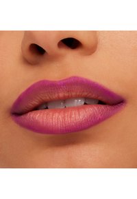 Nærbilde av lepper med en gradient i nyanser av rosa og lilla, med en matt tekstur og synlige fine linjer på huden.