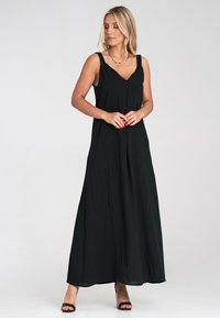 Schwarzes Maxikleid mit V-Ausschnitt, verstellbaren Trägern und einem fließenden Schnitt. Der Stoff wirkt leicht und hat eine weiche Textur.