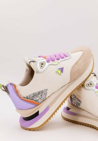 Sneakers med en vit, slät ovandel, beige och lila detaljer, silverfärgad utrustning, texturerade lila snören och glittriga sidodetaljer.