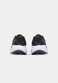 Black athletic shoes with a textured upper, white midsole, and rubber outsole featuring a patterned grip. Rear view highlights curved design.