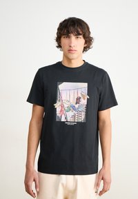Svart bomull t-skjorte med et fargerikt grafisk design av sneakers på en klessnor, med rektangulær krage og korte ermer.