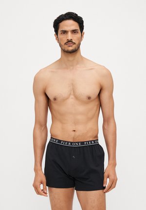 Boxer shorts neri in cotone con cintura elastica, dotati di testo bianco "PIER ONE" e apertura con bottone, indossati da un uomo senza maglietta.
