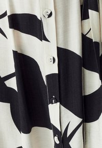 Hemd mit Knöpfen in einem schwarz-weißen abstrakten Muster, leichtem Stoff, geradem Schnitt und fünf Knöpfen auf der Vorderseite.