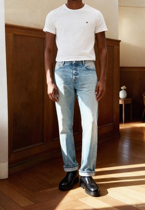 White cotton short-sleeve t-shirt with a small logo, faded light blue denim jeans, and black leather shoes with a chunky sole.