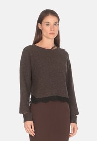 Maglione a coste marrone con design cropped, caratterizzato da un bordo in pizzo nero nella parte inferiore e maniche lunghe con polsini aderenti.