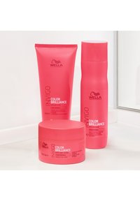 Set van drie haarverzorgingsproducten in felroze verpakkingen: een tube, een fles en een pot, gelabeld "Color Brilliance" van Wella.