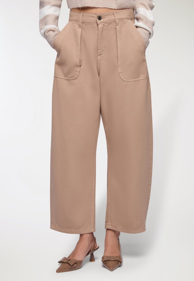 Pantaloni beige a gamba larga con tasche anteriori, realizzati in tessuto misto cotone. Presentano una vita alta e un orlo pulito.