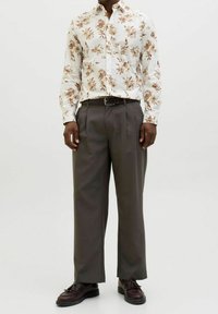 Květovaná bílá košile s dlouhým rukávem a hnědými prvky; v kombinaci s volnými tmavě šedými kalhotami s vysokým pasem; texturovaná látka; klasický límec.