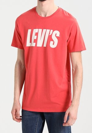 Rød bomulds t-shirt med et stort hvidt "LEVI'S" logo på fronten, korte ærmer og rund halsudskæring. Casual fit og glat tekstur.