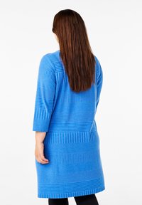 Abito blu lavorato a maglia con motivi a righe orizzontali, maniche a tre quarti, vestibilità ampia e design di lunghezza media. La texture appare morbida.
