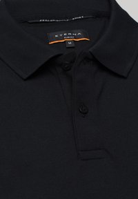 Sorte slim-fit polo-shirt lavet af tekstureret stof, med krave, tre knapper og et mærke med "ETERNA" og størrelse "M."
