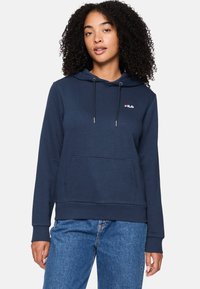 Sudadera azul marino hecha de tela suave, con un bolsillo frontal, cordones y un pequeño logo blanco en el pecho.