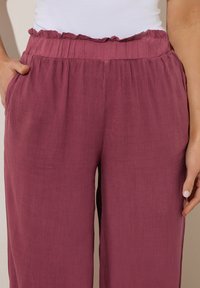 Roze wijde broek met een gerimpelde tailleband, voorzien van zijzakken en een lichte, gestructureerde stof.
