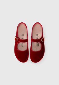 Zapatos Mary Jane de terciopelo rojo con puntera redondeada, tira en el tobillo, hebilla dorada y suela plana. El interior cuenta con una plantilla acolchada de la marca.