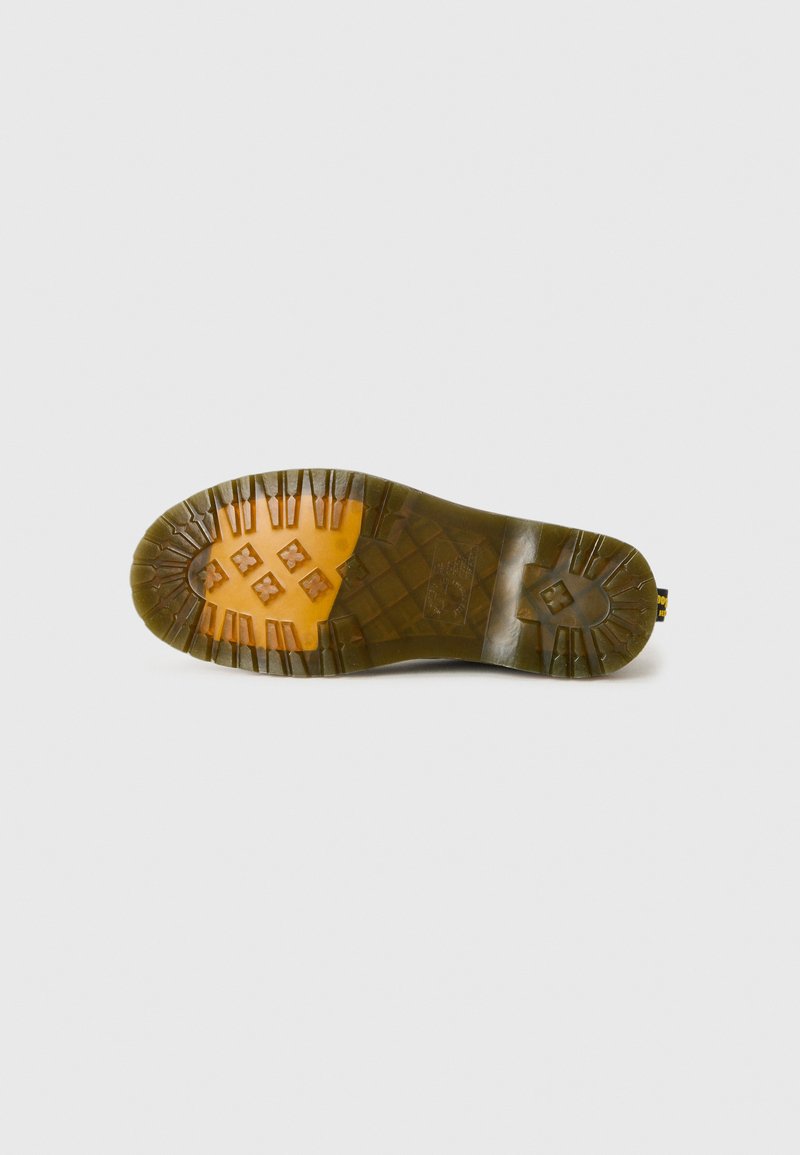 Green rubber sole with a textured pattern and an orange midsole section, featuring deep treads for traction. Designed for durability.