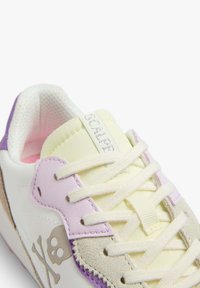 White sneaker with light yellow and purple accents, suede and smooth leather materials, flat laces, and a decorative skull detail.