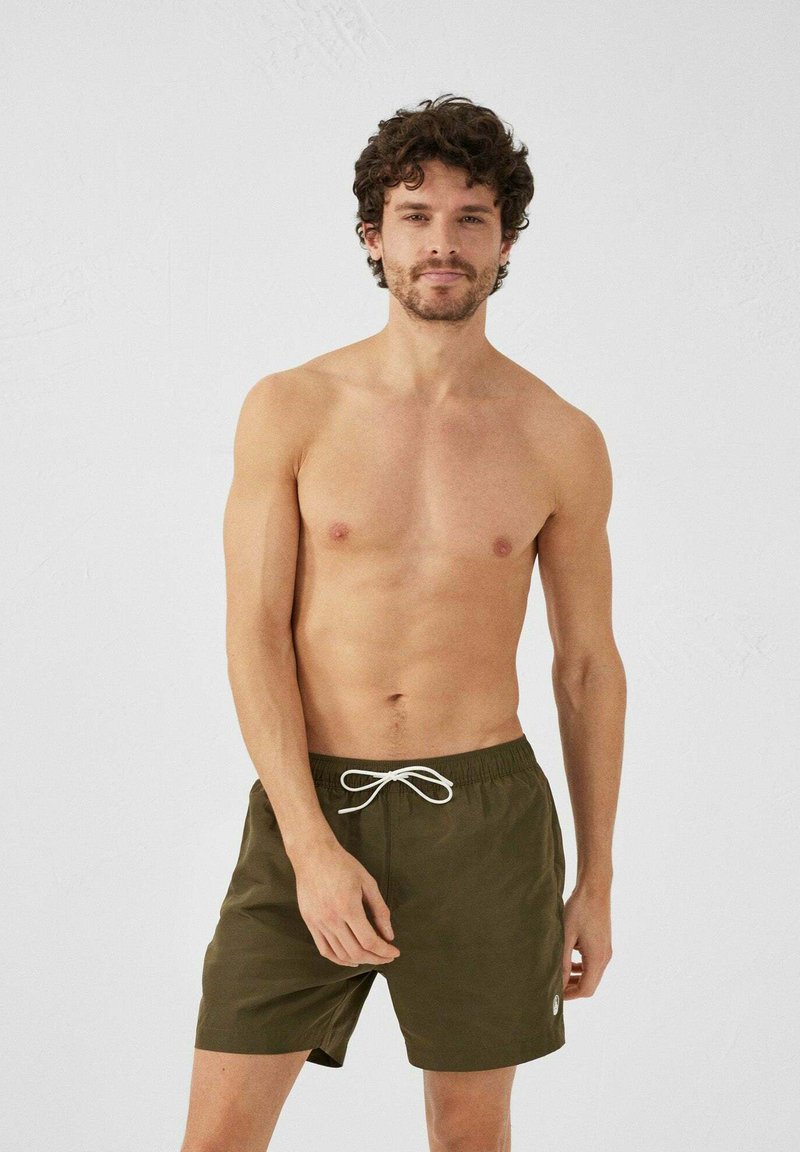 Khaki zwembroek met een trekkoord in de taille, met een gladde textuur en een logo detail aan de zijkant, gedragen door een blootboven-lichaam mannelijke model.
