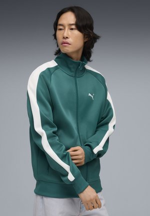 Green zip-up jacket with white stripes, made of smooth fabric. Features a high collar and logo on the chest. Classic athletic design.