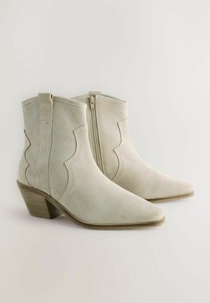 Vaaleanharmaat mokkanahkaiset nilkkurit, joissa on siksak-kuvio, terävä kärki ja pinottu korko. Sivuvetoketju helppoa pukemista varten.