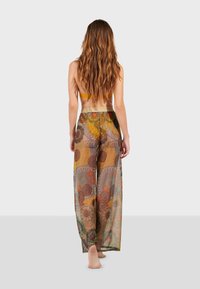 Pantalones palazzo fluidos y translúcidos con un colorido estampado floral y geométrico, con una cinturilla elástica y un corte relajado.