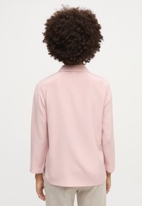 Helles rosa Langarmhemd mit Kragen, glatter Textur und seitlichen Schlitzen. Die Rückseite weist ein klassisches, minimalistisches Design auf.