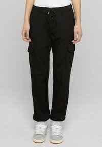 Mustad tööpüksid elastse vöökohaga ja nöörpingutusega. Omavad kahte küljetaskut ja lõdvestunud lõiget. Sobitatud hallide tossudega.