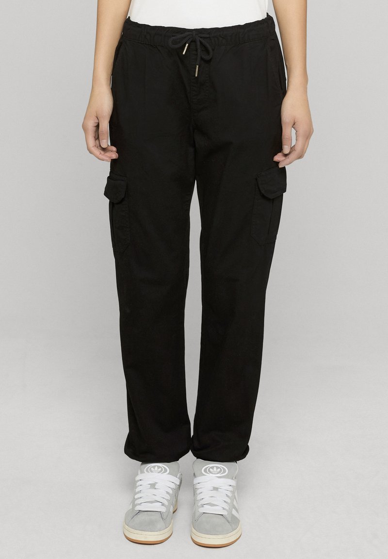 Mustad tööpüksid elastse vöökohaga ja nöörpingutusega. Omavad kahte küljetaskut ja lõdvestunud lõiget. Sobitatud hallide tossudega.