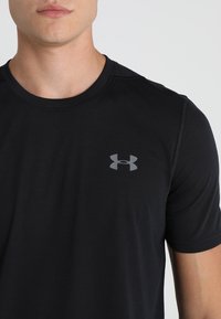 Schwarzes, kurzärmliges Sport-T-Shirt aus glattem Stoff, mit einem grauen Logo auf der Brust und einem Rundhalsausschnitt. Nahtdetails sind sichtbar.