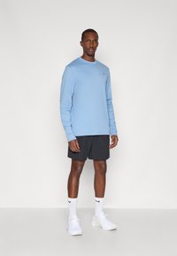 Šviesiai mėlyna ilgomis rankovėmis palaidinė, juodos šortai, balti sportiniai bateliai ir balti kojinai su juodu logotipu. Paprastas dizainas, laisvas stilius.