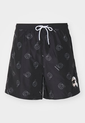 Zwarte zwemshorts met een herhaald wit omtrekpatroon van gestileerde hoofden, elastische tailleband met trekkoord en zijaccenten.