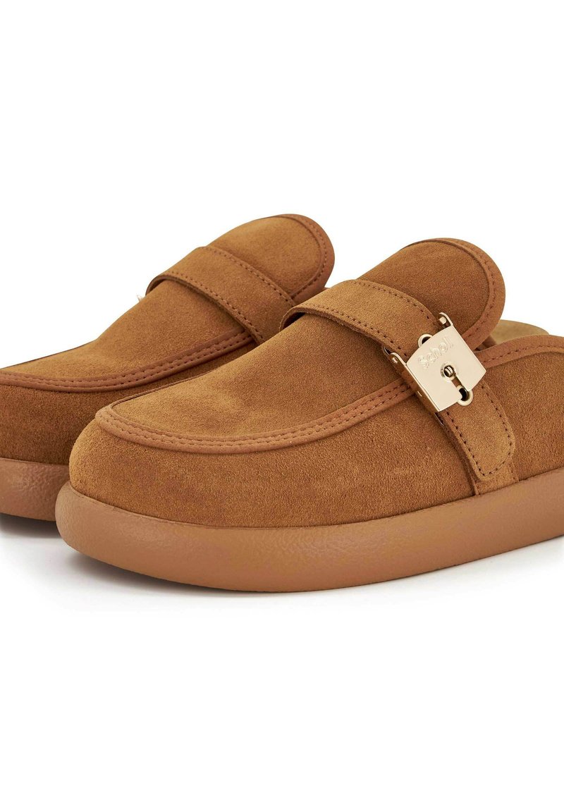 Scarpe slip-on in suede marrone con punta rotonda, una fascia nella parte superiore e un dettaglio a fibbia in tonalità oro sul lato.