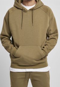 Khaki mikina s kapucí, vybavená prostornou přední kapsou, šňůrkami a žebrovanými manžetami. Měkká látka s pohodlným a volným střihem.