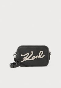 Borsa rettangolare in pelle nera con finitura testurizzata, caratterizzata da un logo "Karl" glitterato in argento sul fronte e una tracolla regolabile.