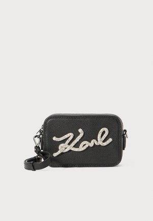 Black leather rectangular bag with a textured finish, featuring a glittery silver "Karl" logo on the front and an adjustable strap.