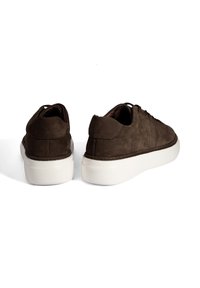 Braune Wildledersneaker mit runder Zehenform, minimalen Nähten und weißer Gummisohle. Das Design zeichnet sich durch eine niedrige Profilhöhe und eine Schnürung aus.