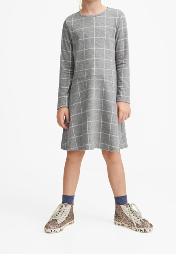 Enfant portant une robe à manches longues grise à motif de grille blanche, des chaussettes bleues et des baskets montantes scintillantes avec du texte sur les semelles.