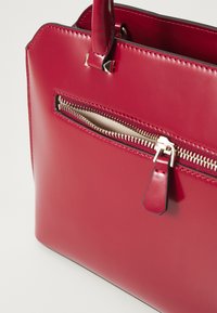 Borsa in vernice rossa con chiusura superiore a zip, dotata di una piccola tasca esterna con zip e accentuata da hardware argentato.