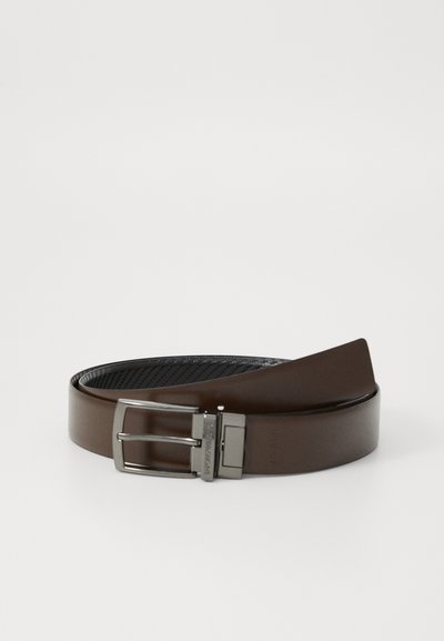 Curea din piele maro cu un finisaj neted, având o cataramă din metal de culoare argintie. Curea este plată, cu un design elegant și fără modele vizibile.
