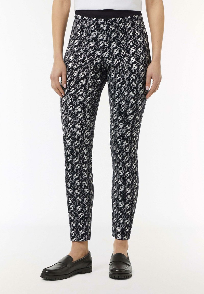 Marineblauwe leggings met een wit patroon van ovale vormen. Elastische tailleband, aansluitende pasvorm en zachte, rekbare stof. Gemaakt in combinatie met zwarte instappers.