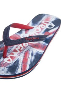 Kipšas su mėlynai raudonu Jungtinės Karalystės vėliavos dizainu, tekstūruotais juodais diržais ir raudona "Pepe Jeans" logotipu ant diržo.