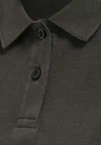 Donkergroene polo shirt van een textuurstof. Voorzien van een knoopsluiting en een klassieke kraag, benadrukt door zwarte knopen.