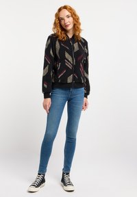 Zwarte bomberjack met een gestructureerde fleece afwerking, voorzien van een kleurrijk geometrisch patroon, een ritsluiting en ribgebreide manchetten en zoom.